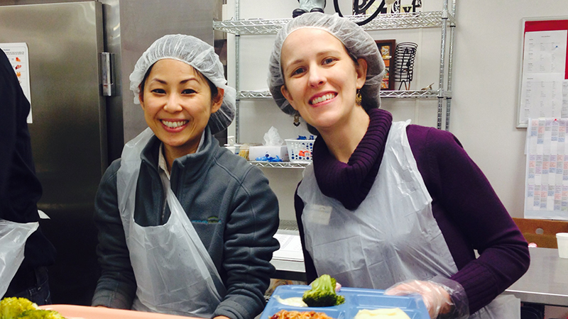 Two women happily cooking together in a kitchen.