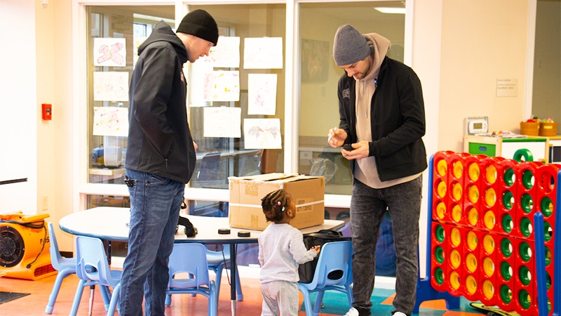 A man and a child in a classroom, engaged in a learning activity.